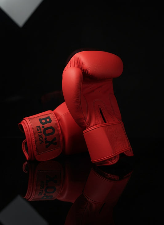Boxhandschuhe in Cardinal Red aus echtem Leder, ein Handschuh in Rückansicht der andere seitlich dahinter platziert hochwertige Ausrüstung für Boxen und Kickboxen