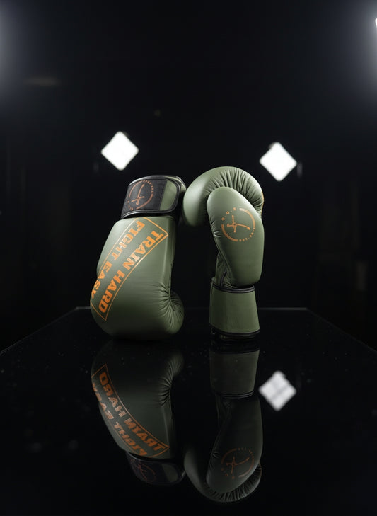 Boxhandschuhe in Military orange aus echtem Leder, ein Handschuh in Vorderansicht mit Logo der andere seitlich dahinter strapazierfähige Premium Ausrüstung für Boxen und Kickboxen